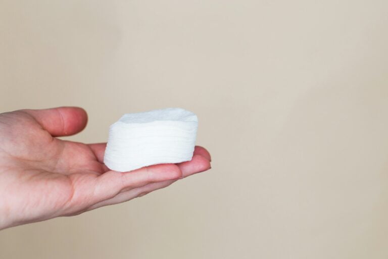Hands of a woman holding cotton swabs on a beige background