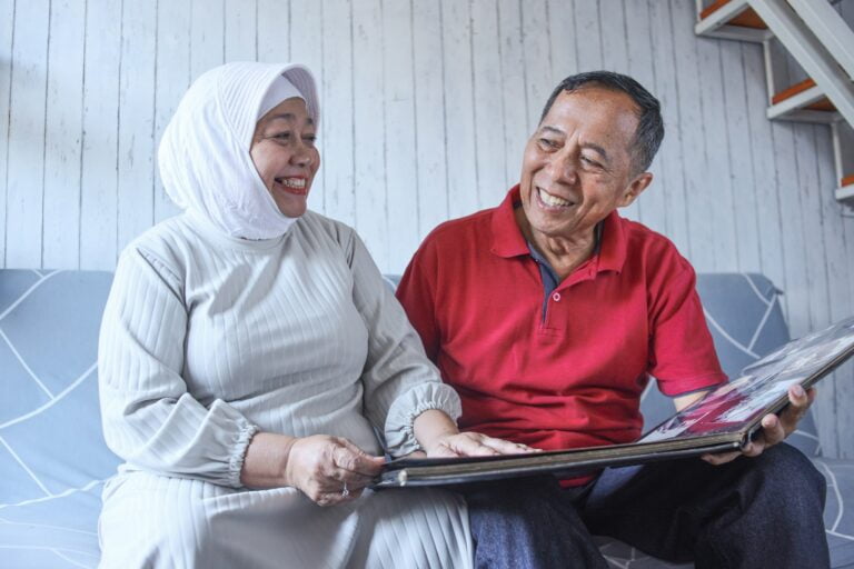Senior couple sitting on sofa while looking their memory photo album